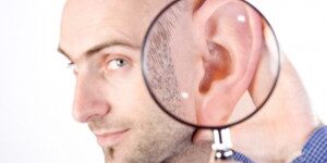 Im Listening A portrait of a Caucasian adult male on a white background holding a magnifying glass to his ear to indicate that he is listening.